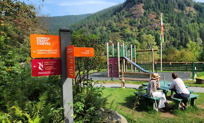 A couple sitting in the sunshine by a play area